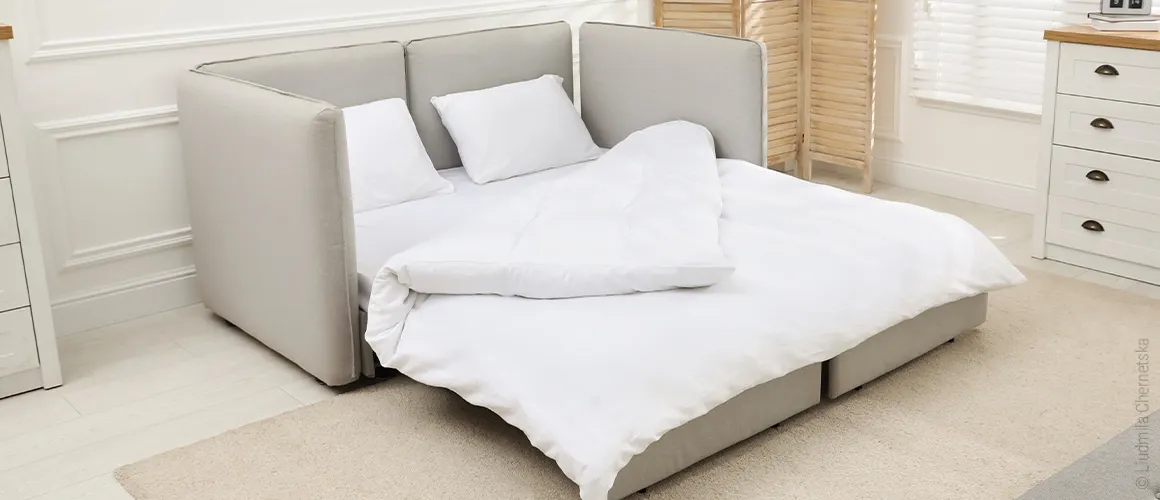 Foto: Auf einer Ausziehcouch liegt ein Topper 160x200 und darauf Bettzeug für zwei Personen.