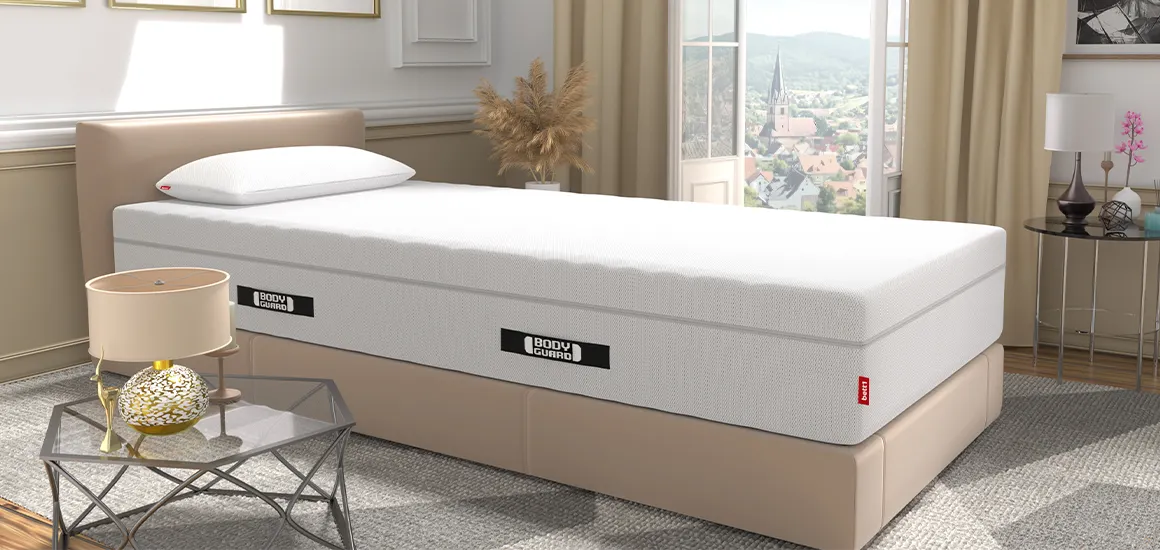 Materac BODYGUARD Boxspring na beżowym łóżku w nowoczesnej sypialni z otwartymi drzwiami balkonowymi.