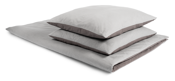 Auf einer zusammengelegten Bettdecke liegen zwei Kissen ordentlich übereinander. Das Bettzeug ist mit Winter-Bettwäsche 200x220 bezogen.