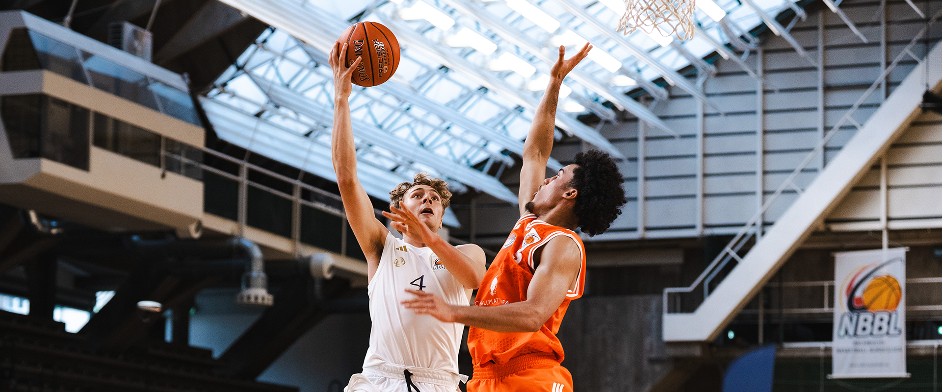 Dwóch mężczyzn w czasie meczu koszykówki, w podskoku do piłki.