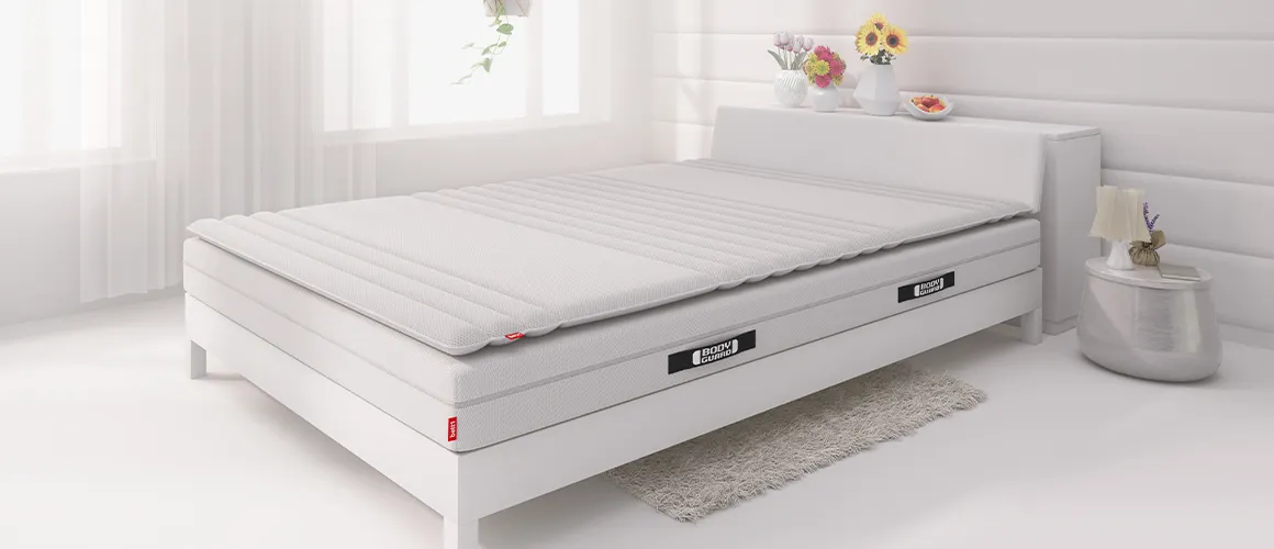 Fragment sypialni z łóżkiem, materacem BODYGUARD oraz topperem.