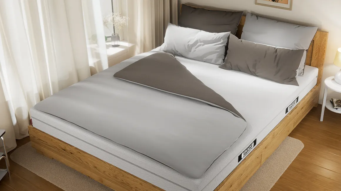 Foto: In einem Doppelbett liegt eine Paardecke in Bettwäsche 200x220 und vier Kissen.