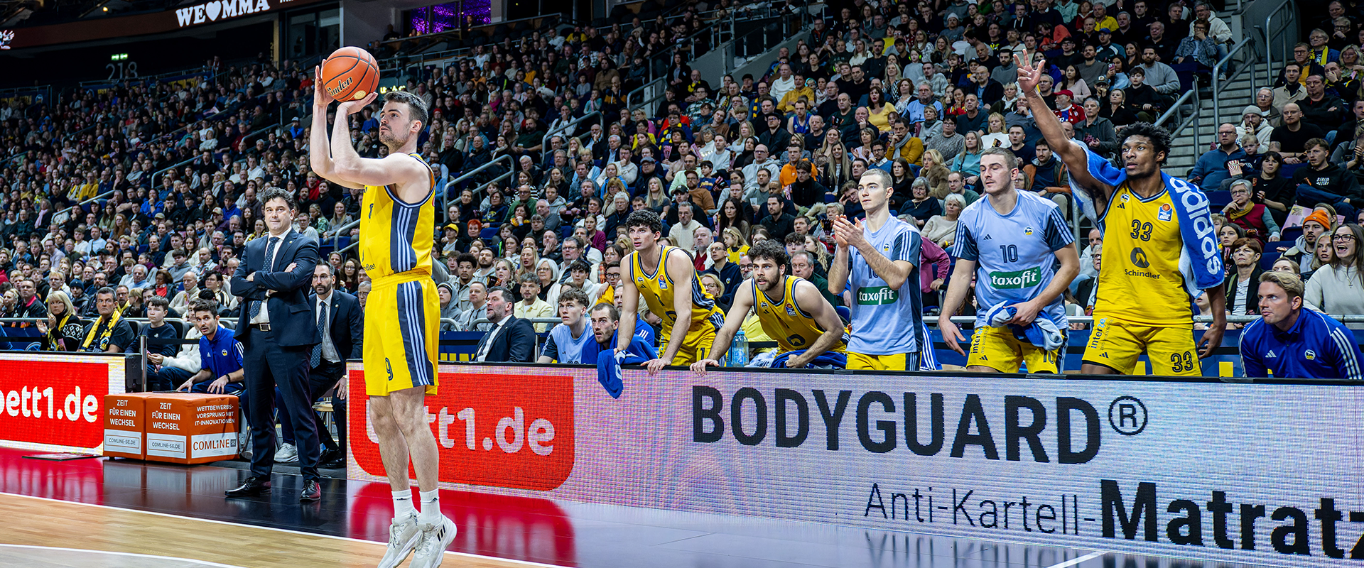Członek drużyny Alba Berlin wrzucający piłkę do kosza podczas meczu.
