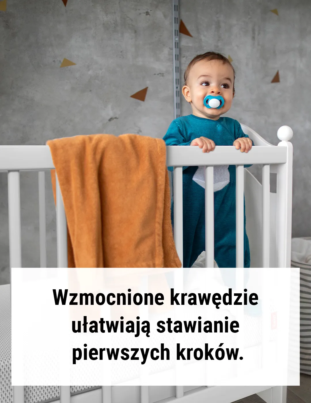 Dziecko stoi w łóżeczku. Tekst: Wzmocnione krawędzie ułatwiają stawianie pierwszych kroków.